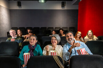 Diverse group enjoying movie and eating popcorn in cinema