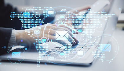 Businessperson typing on laptop with digital email icons and global map overlay representing communication technology concept on light background.