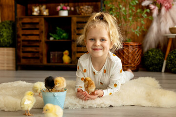 Cute sweet little children, blond boy and girl, playing with little chicks at home,