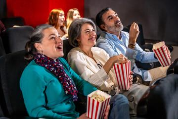 Group of friends enjoying a movie and eating popcorn in a cinema