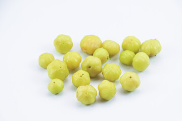 Scattered Phyllanthus acidus fruits on white