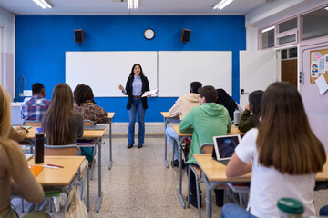 Teacher explaining lesson to students in classroom at high school