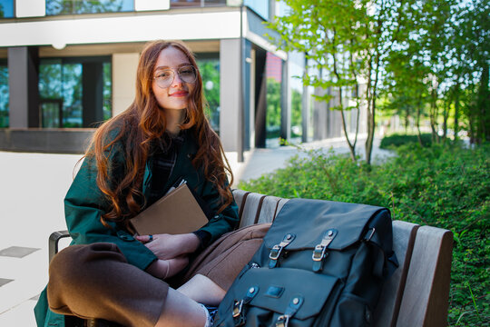 Ginger girl student in eyeglasses near the university portrait