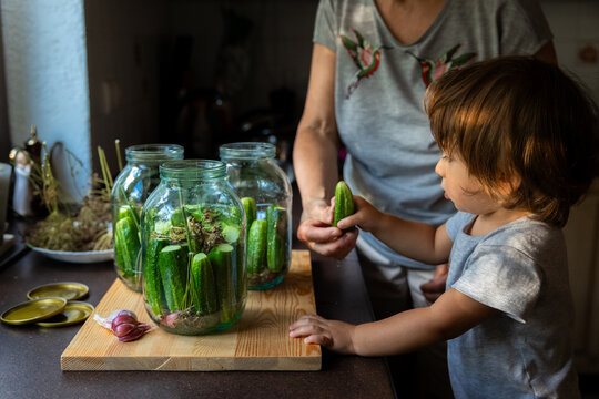 Child helps with pickling cucumbers in a cozy kitchen