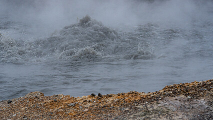 Detailaufnahme eines kochenden Schlammtopfs im Geothermalgebiet Krysuvik-Seltun in Island, Schlamm blubbert, Dampf steigt auf, seitlich sind Schlammtropfen zu erkennen