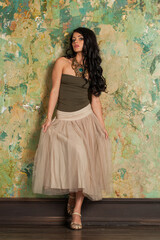 Cute young fashion woman standing against green stucco wall background