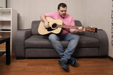 Music Practice Session at Home with Man Playing Guitar While Sitting on Comfortable Couch
