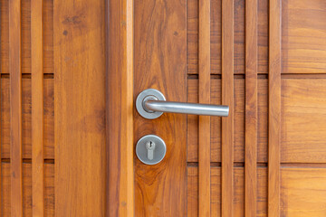 Stainless steel door handle on wooden door.