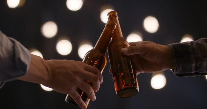 Slow clinking of beer bottles in male hands emotional moment of connection pause in celebration with warm lights and cinematic feel symbolizing unity friendship and unspoken understanding