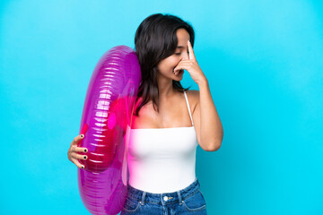 Young hispanic woman holding air mattress donut isolated on blue background laughing