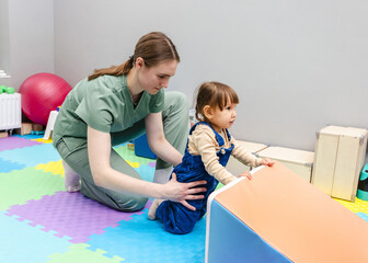 Physiotherapist assisting young child with coordination exercise in rehabilitation center. Neurological rehabilitation for child with therapeutic physiotherapy