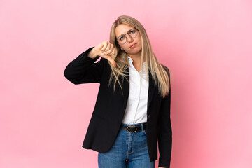 Business blonde woman isolated on pink background showing thumb down with negative expression