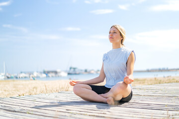 Young blonde woman at outdoors doing yoga
