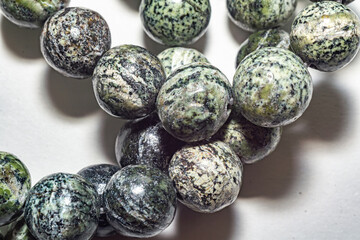 Delicate and charming spotted green serpentine beads, ideal for jewelry, crafts, or decor. Close up photo, perfect for enhancing various creative projects. Decorative beads of natural serpentine beads