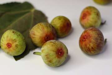 Fresh figs with green leaves on a white background