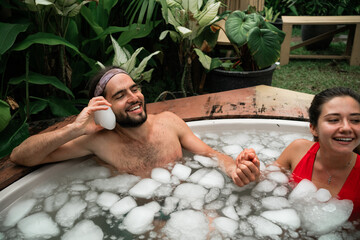 Man and woman take an ice bath outdoors in a tropical setting. Cold plunge for health, recovery, and resilience. A trending wellness practice combining nature, biohacking, and therapy