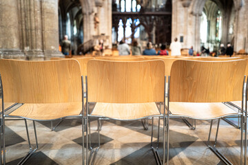Rows of wooden seats seen on a famous English cathedral, used by congregations of the cathedral. Visitors can be seen in the background.