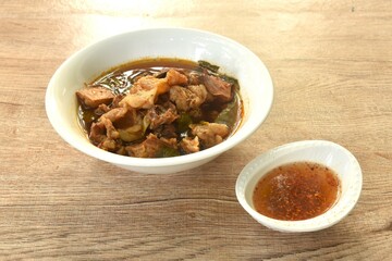 boiled braised beef meat and tendon in herb brown soup on bowl dipping spicy chili sauce 