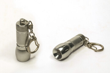 Two small LED flashlights in the form of keychains on a white background.