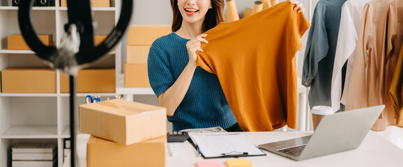 Fashion blogger concept. Young Asian women selling clothes on video streaming.Startup small...
