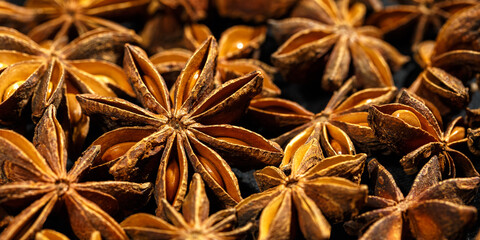 Anise stars texture background, above view close up flavor spices dried anise seeds on dark, banner with natural condiments, aromatic ingredient for cooking drink and food