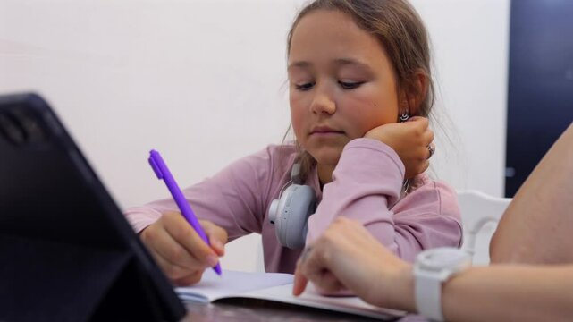 Mother and daughter sitting together, using a tablet for homework. A scene of home schooling and online education. Perfect for themes of learning, parenting, or technology in education.