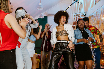 A group of friends of different ethnicities in their late 20s dressed in stylish clothes dancing...