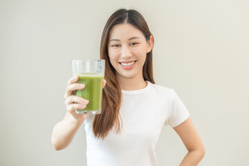 Green detox juice concept, Beautiful asian young woman hand holding vegetable smoothie glass for...