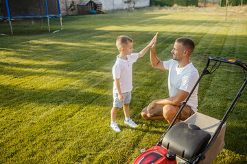 Teamwork. Father and his little son giving high five to each other for finishing their gardening...