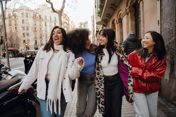 A group of four young female friends in their late 20s, having fun and joking around as they take a...