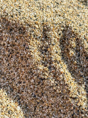 natural sand texture, a detailed look at a sand mound with a mix of beige, brown, and black grains, alongside various sized pebbles