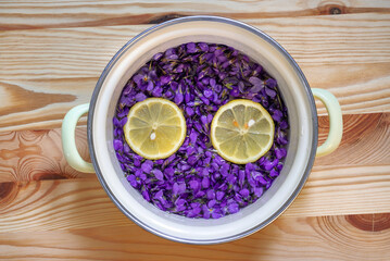 Violet flowers (Viola odorata) in a pot with lemon slices for syrup arranged like a face