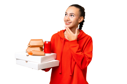 Young Arab woman holding fast food over isolated background looking up while smiling