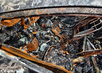 Charred remnants of a vehicle interior left behind after a devastating fire incident