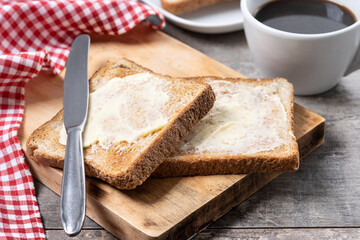 Sliced fresh bread with butter and coffee for breakfast on wooden table