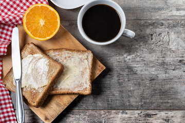Sliced fresh bread with butter and coffee for breakfast on wooden table. Top view. Copy space