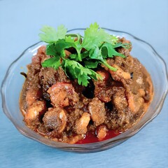 A flavorful bowl of prawn masala curry, rich in spices and garnished with fresh coriander leaves.