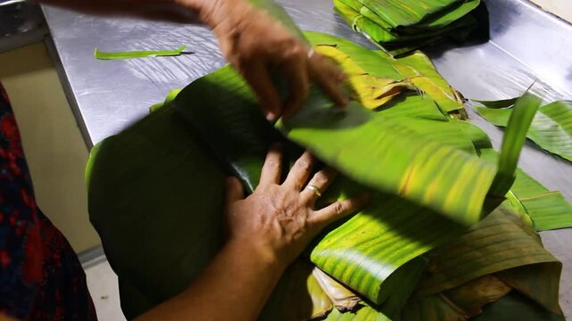 An unrecognizable person's hands wrapping a delicious Quesillo in banana leaves on a table in Yaguar&aacute;, Huila, Colombia. Colombian food concept