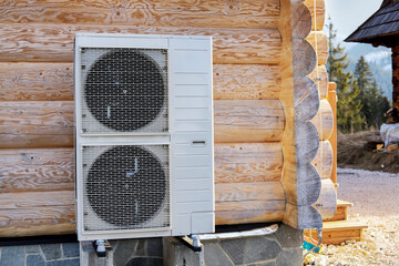 A large air conditioner located outside a wooden building.