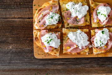 Pinsa Romana with mortadella, burrata cheese and pistachio on wooden table	