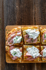 Pinsa Romana with mortadella, burrata cheese and pistachio on wooden table	