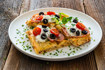 Pinsa Romana with mortadella, burrata cheese, black olives and cherry tomatoes on wooden table	