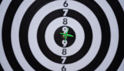 Green dart hitting the bullseye on a black and white target. Concept of precision, accuracy,...