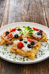 Pinsa Romana with mortadella, burrata cheese, black olives and cherry tomatoes on wooden table	