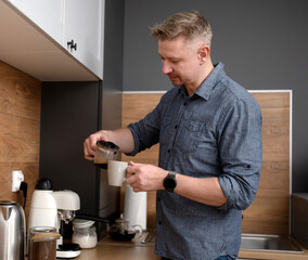 Handsome Man Pouring Himself Coffee At Home In The Kitchen