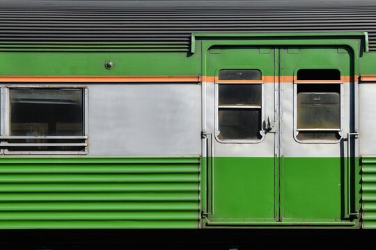 glass door and window of a green train carriage under sunlight, old classic train carriage waiting for maintenance and repair at platform