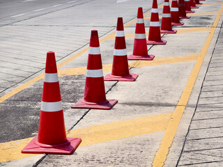 A row of red and white traffic cones is placed by a road