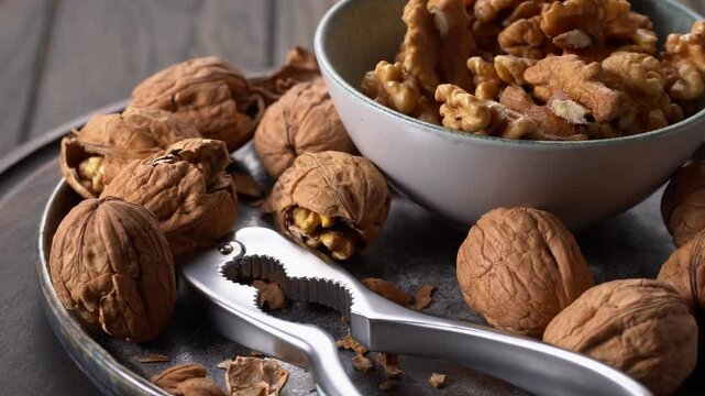 Plate of walnuts and bowl of walnut halves with nutcracker tool rotation