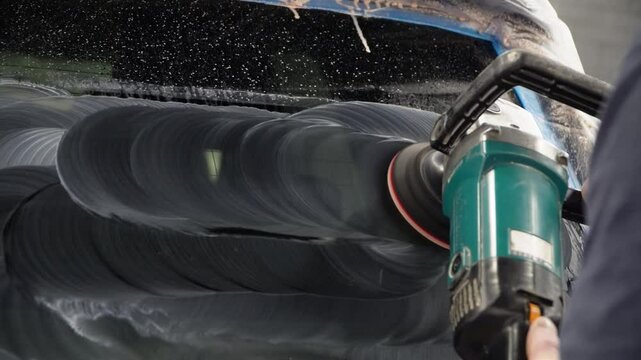 A man polishes the glass of a car with a polishing machine from small scratches with a large one. Auto glass repair, replacement. Car detailing. Hands with an orbital polishing machine. Close-up.