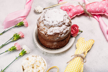 Easter Easter cake, Easter bread with cottage cheese, sprinkled with powdered sugar on a light background, next to Easter eggs, yellow ribbon, rag doll Easter bunny
